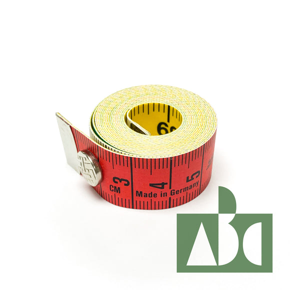 Product photo of a rolled up sewing tape measure. The tape is fastened with a small metal button. One side of the tape is red, and the other yellow. 